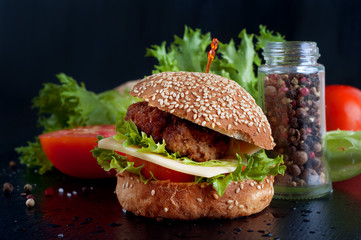 Hamburger with salad, tomato, meat on black  backdrop
