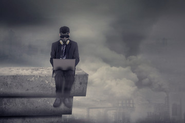 Man with gas mask uses laptop on rooftop