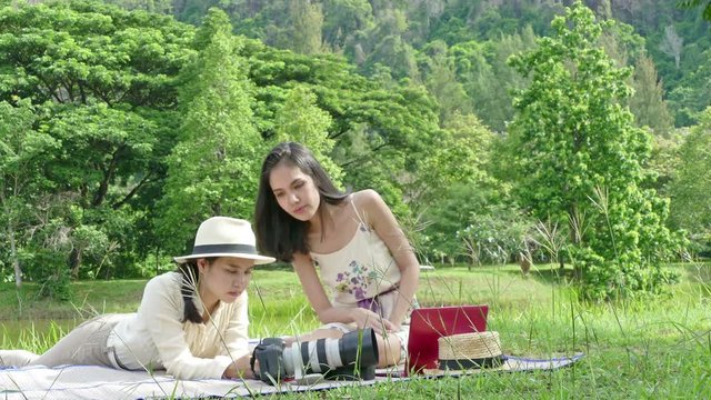 two women are relax in the nation park. a women and a Equestrian girl eat snacks take a photo,working with laptop while they are relax in the nation park