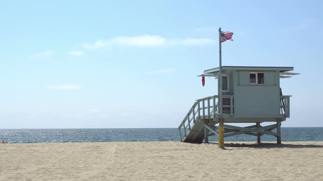Lifeguard tower on an empty Los Angeles beach shot on a bright and sunny summer day, clear blue sky and ocean horizon in the background