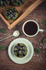 Vintage photo, Fresh muffins with spinach, desiccated coconut, chocolate glaze and cup of coffee, delicious healthy dessert