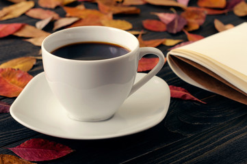 Cup coffee on wooden table with autumn dry leaves