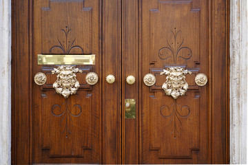 golden colored heads as door handle of an old wooden door