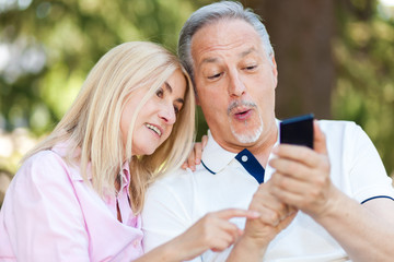 Portrait of a mature couple taking a self portrait in a park