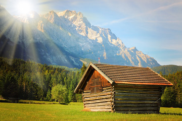 Sunrise over Zugspitze. It is Germany's highest peak (2962 m). View from a Garmisch Partenkirchen valey. Old hayloft in mountain landscape, Bavaria, Germany. Warm filtered picture.