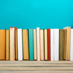 Books on grunge wooden table desk shelf in library. Back to school background with copy space for your ad text. Old hardback   no labels, blank spine