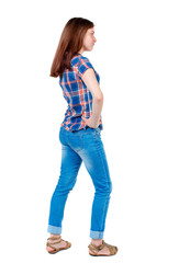 back view of standing young beautiful  woman.  girl  watching. Rear view people collection.  backside view of person. Girl in plaid shirt standing sideways with hands on hips.  