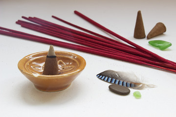Aroma sticks and cones on white background with blue feather and pebbles