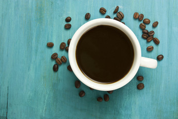 White cup of coffee with coffee beans scattered around it