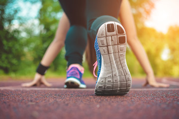 Female runner ready for running sprint. Woman in starting line runner pose for training in a park.