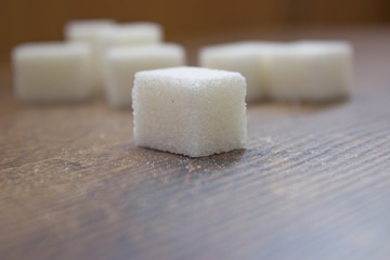 Sugar cube close up view on a wooden background.