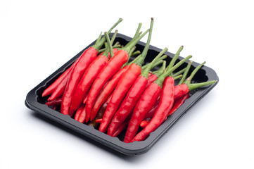 Heap of red hot chili pepper in black container on white backgro