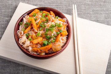 Asian dish of rice noodles in a small brown wooden bowl