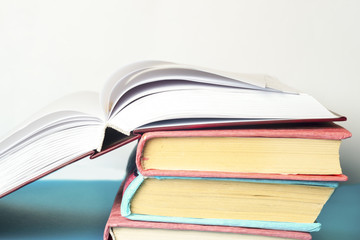 Open book, stack of colorful hardback books on light table. Back
