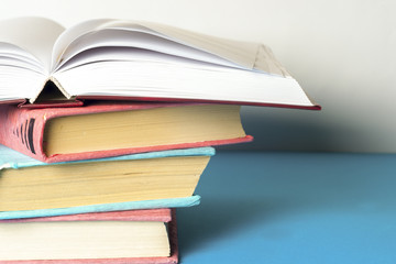 Open book, stack of colorful hardback books on light table. Back