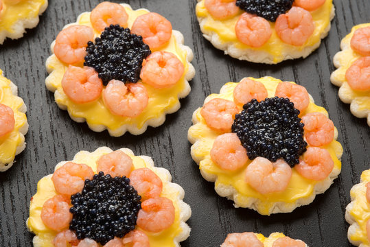 Tartine rotonde con code di gamberetti e uova di lompo