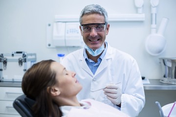 Fototapeta premium Smiling Dentist examining a patient with tools