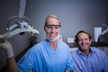 Smiling dental assistant adjusting light in clinic