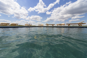 Obraz premium Amazing views over the pool area with wooden sun loungers.