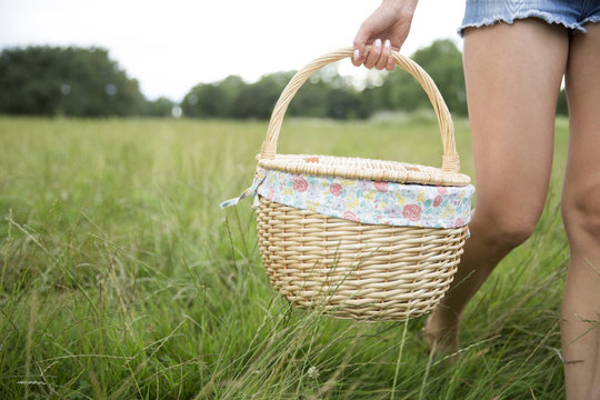 Close Up Of Woman Carrying Picnic Basket In Countryside