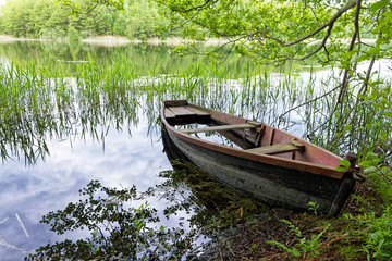 Fototapeta na wymiar Abandoned wooden fishing boat at lake shore