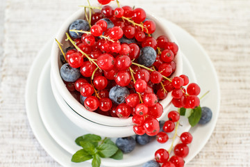 Blueberries and redcurrant in white bowl on a table