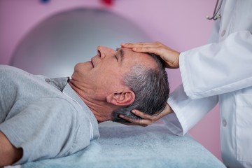 Fototapeta na wymiar Senior man receiving head massage from physiotherapist