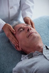 Obraz na płótnie Canvas Senior man receiving head massage from physiotherapist