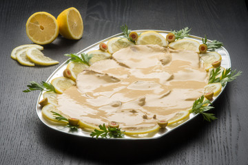 Vassoio da portata con vitello tonnato su un tavolo nero di legno