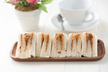 finger sandwiches triangles in wooden plate on white table