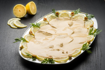 Vassoio da portata con vitello tonnato su un tavolo nero di legno