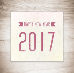 Happy new year 2017 on vintage paper over wood background