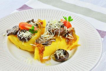 Fried polenta triangles with mushrooms and cheese on plate.