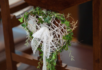 Handcrafted heart-shape wedding decoration in bohemian style. A wreath of green leaves, decorated with white lace. A wedding in the garden, love, romance, summer. Valentine's day.