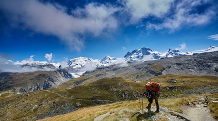Fototapeta na wymiar tired hiker with backpack on the trail in the Apls mountains. Trek near Matterhorn mount