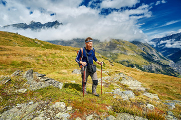 hiker at the top of a pass with backpack enjoy sunny day in Alps. Switzerland, Trek near Matterhorn mount.