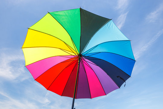 open colorful rainbow umbrella on blue sky background