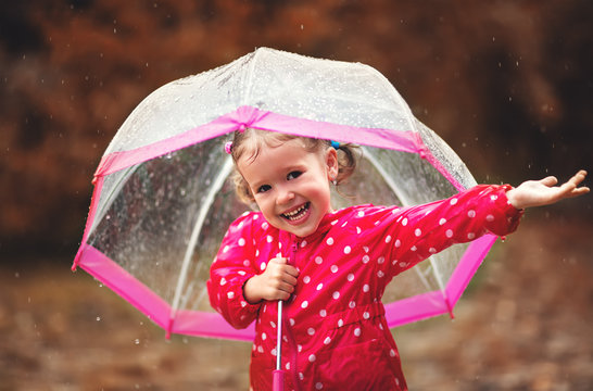 happy child girl laughing with an umbrella in rain