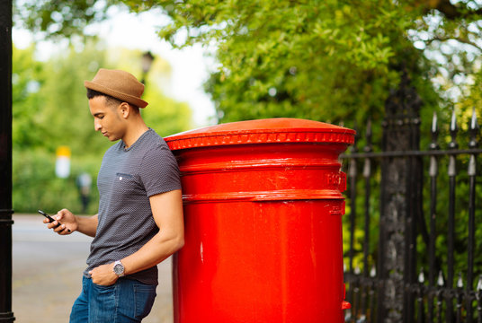 Man leaning against mailbox using smartphone