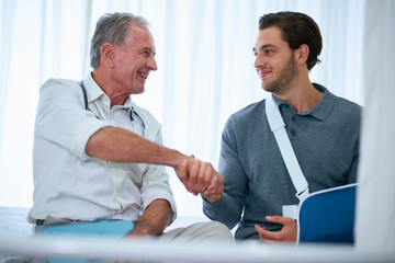 Doctor shaking hands with man in arm sling