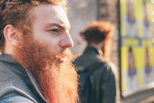 Young male hipster twins with red hair and beards on city street
