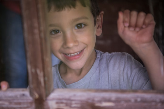 Boy Knocking On Window Looking At Camera Smiling