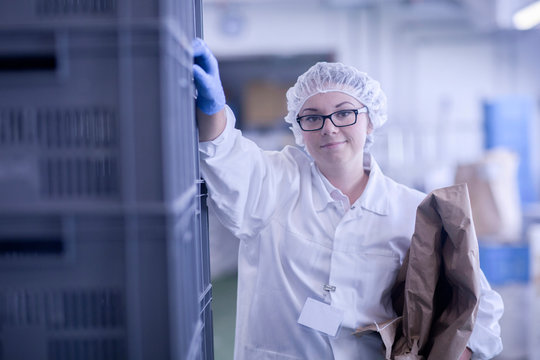 Factory worker holding packaging looking at camera smiling