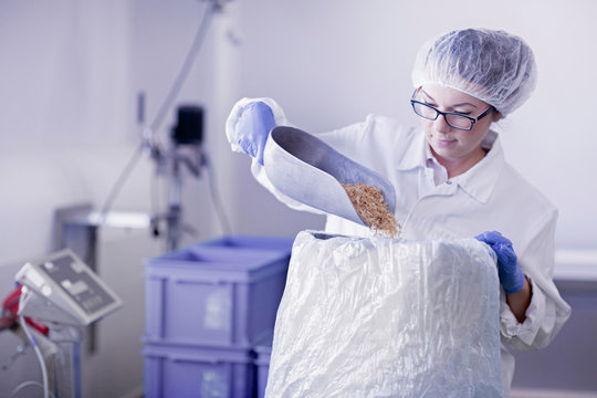 Factory worker scooping food into sack