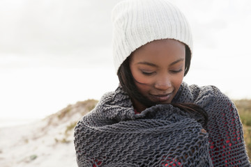 Young woman wrapped in knitted shawl on cold day