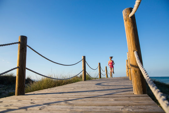 Young woman running  on wooden pathway, low angle view