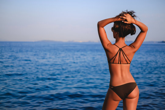 Tanned girl looking at horizon and lifting hair up