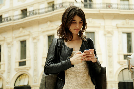 Woman reading smartphone text in Galleria Vittorio Emanuele II, Milan, Italy