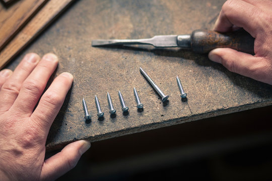 Hand holding chisel, screws in a row