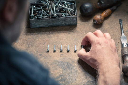 Man arranging screws of similar size in a row